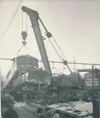 TEXT PÅ KORT:
Nässjö katastrofkran i arbete efter järnvägsolyckan i Kil, tåg 4872 den 14 januari 1949. Kranen lyfte omedelbart upp ena änden av loket, varefter vagnarna lätt kunde bortföras. Därefter sänktes loket varsamt ned på rälen. Arbetet förlöpte utan missöde. Det var första gången denna kran var använd i effektiv tjänst. Kranens vikt 115,5 ton, lyftförmåga 50 ton, tillverkad i England.