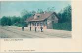 Stationspersonal framför Kilsmo järnvägsstation. Kolorerat vykort från början av 1900-talet.
