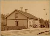 Kungsängens järnvägsstation. Mannen till vänster var Otto Lindbohm, född 1845 och som var stationsinspektor på Kungsängens järnvägsstation 1876-1909. Kvinnan som tittar ut genom fönstret hette Karin.