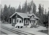 Långsjön efter ombyggnaden. Banvaktstugan har blivit stationshus. Långsjö-Pelle sitter på verandan och läser.