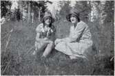 Småjäntorna: syskonen Ingeborg och Siri sittandes i gröngräset iklädda sina fina stråhattar.