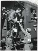 Röda korssyster överlämnar förnödenheter till skadade tyska soldater som är ombord på ett tyskt sjukvårdståg i Hallsberg under Andra Världskriget.