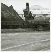 Utlastning av slig i Stråssa. Trafikaktiebolaget Grängesberg – Oxelösunds Järnvägar, TGOJ M4 4345 till höger.