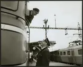 Statens Järnvägar, SJ Rb 1005 och Trafikaktiebolaget Grängesberg - Oxelösunds Järnvägar, TGOJ motorvagnståg, lokförare i samtal vid stationen i Flen maj 1964.
