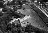 Fågelvy av Alingsås Bryggeri med järnvägsspår till höger i bild och bostadsområden bakom bryggeriet.