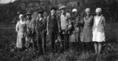 Betskörd på Lövagård. Fyra män och fyra kvinnor i olika åldrar står arbetsklädda och håller i stora betor. Kvinnorna har hucklen och männen kepsar. (Se även bild EA0549)