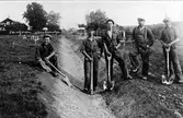 Fem män står kring ett dräneringsdike på ett vägbygge mellan Alingsås-Vårgårda. Männen är så kallade AK-arbetare, och tillhörde lag 4.