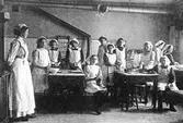 Alingsås första skolkök omkring 1906 i Gamla folkskolan, nuvarande Lendahlskolan. Från vänster Fröken Broman, Hilda Olander, Hilda Bergstrand, Alice Brask, Edith Sandin, Rut Dalgren, Greta Skarin, Svea Klinge, Anna Hasselskog, Edit Edholm. Sittande: Dagny Sjöström och Ida Johansson.