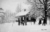 VUXNA OCH BARN I SNÖN FRAMFÖR ETT BOSTADSHUS