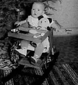 ETT LITET BARN I EN BARNSTOL INTILL JULGRANEN