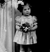 EN LITEN FLICKA MED EN BLOMBUKETT I HANDEN.