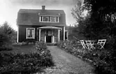 EXTERIÖR AV BOSTADSHUS.  TRÄDGÅRDSMÖBEL FRAMFÖR HUSET