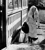 EN FLICKA GÅR UPPFÖR EN TRAPPA OCH BÄR PÅ EN VIDBRÄTTAD HATT