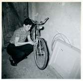 Sylve Wall sitter på huk och lagar en cykel.