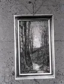 En bild på en målning föreställandes träd och ett vattendrag. Fäst med några knappnålar.