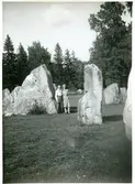 Badelunda sn, Anundshögsområdet, Långby.
Kvinna och man står mellan stenar i skepssättning.