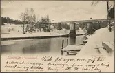 Ett vintrigt Södertälje kanal med järnvägsbro.