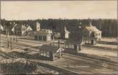 Vy på stationsområde och del av bangård med ställverk i bakgrunden.