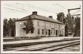Stationshus och perrong vid elektrifierad bangård.