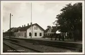 Stationsområde med perrong i bild och bebyggelse i bakgrunden.