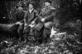 Tre skogsarbetare sitter på en nyfälld stock: Viktor i Storåker i mitten med John 