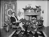Kvinna i bostadsmiljö omgiven av blommor, Östhammar, Uppland, 1964