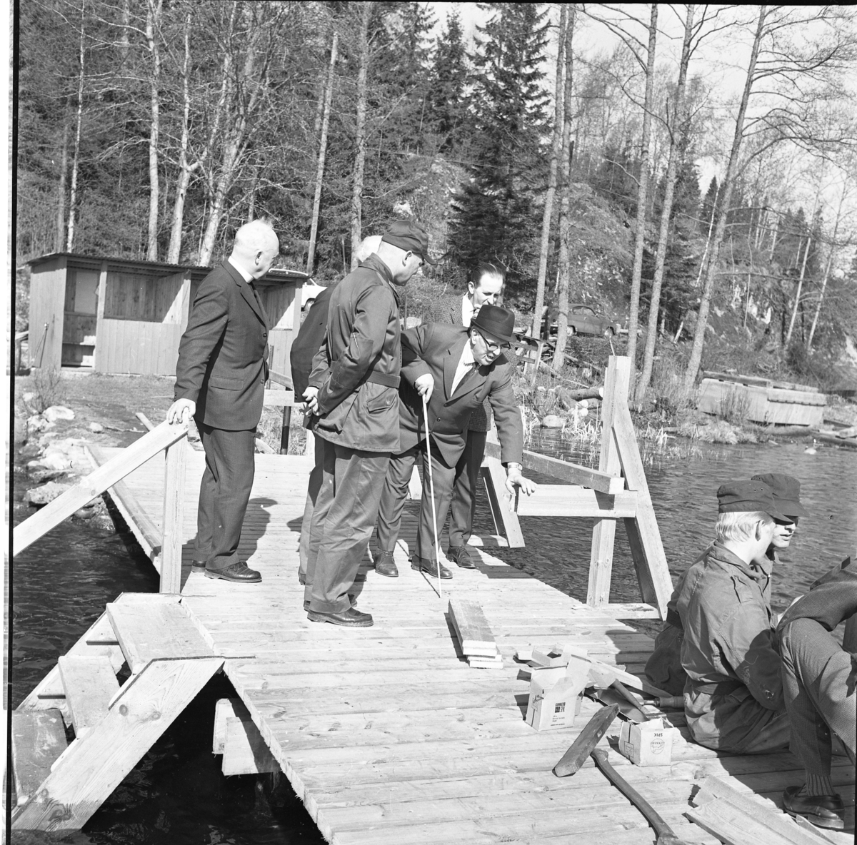 Percy Heldebrandt, Men on a bathing bridge at the Blind Home in Bunn. In the foreground, some younger men are sitting in military attire on the dock among carpenter tools.
