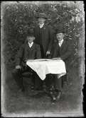 Tre män runt bord
