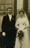 Brudparet Amos och Hildur Wessberg står utan glasverandan till Ekan 1:1 7/10 1911. Ekans/Ekens gård var Hildur Alms föräldrahem. 
Amos Wessberg f. 1885 Torslanda d. 1941 Kållered.
Hildur Alm f. 1888 Ekan, Kållered d. 1971 Kållered, Brattåshemmet.