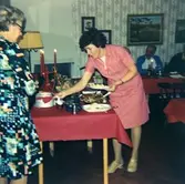 Kokerska Ingela Sjöberg (i röd klänning) i Brattåshemmets matsal, 1970-tal.