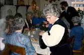 Uppvaktning efter pensionsavgång för Birgit Magnusson (f 1918) hemma i Märta och Gustaf Lindmans lägenhet i Bifrost, Mölndal.
Stående är församlingsassistent Eivor Johansson (håller i kannan). Till vänster sitter Linnéa Olofsson (ryggen åt kameran), Inga Hallbäck (uppsatt hår, Kyrkbacken), Astrid Johansson (Kyrkbacken), Martha Nilsson, okänd, Ingrid Skansing (Livered), Daga Alander (änka efter kantor Gunnar Alander), Stig-Ove Dahlgren (stående) och Anna Nilsson.