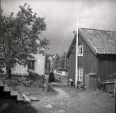 Gårdsmiljö från Figeholm, bostadshus med träfasad sadeltak, trappa och staket.