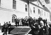 Kung Gustaf V står på scenen framför Rådhuset tillsammans med högtidsklädda män och kvinnor. Några bär uniform. Flaggorna är hissade.
I Arboga firas Riksdagens 500-årsjubileum. Arbogautställningen pågår samtidigt.