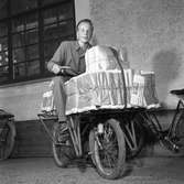 Arboga Tidning, personal.
En ung man sitter på en cykel fullastad med tidningar som ska levereras. Tidningsbuntarna hålls på plats av snören och en lång läderrem.