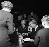 Arbogabor deltar, som publik, vid sändningen av Frukostklubben, ett underhållningsprogram som sänds på lördagsmorgnar. Sigge Fürst är ständig programledare. Här ses han samtala med publiken, som sitter vid runda bord och dricker kaffe.