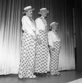 Deltagarna i Arbogarevyn spelar upp sin Jubileumsrevy. På scenen står tre herrar i samma sorts utstyrsel. Mannen längst till vänster kan vara Rune Ström.