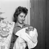 Mor och barn. Kvinna med sitt nyfödda barn i famnen. Barnet är det först födda, i Arboga, på 60-talet.