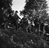 Arbogas Stjärnknutte.
Tävling i terrängkörning med motorcykel. Publiken står alldeles intill banan.