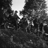 Arbogas Stjärnknutte.
Tävling i terrängkörning med motorcykel. Publiken står alldeles intill banan.