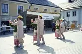 Arbogaträffen
En utländs dansgrupp har uppvisning på en uppbyggd dansbana på Stora torget. I bakgrunden syns Stadsgården och till höger butik Lyktan.