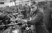 Arne Engström, iklädd skyddsrock, vid en maskin. Industrimiljö.