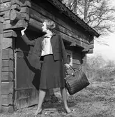 Ateljé Touché. Britt-Marie Utterström visar mode.
Kvinna iklädd dräkt. Hon har en stor väska i handen. Bilden är tagen utomhus intill en äldre timmerbyggnad.
Britt-Marie drev ateljén tillsammans med Marianne Rosenkvist