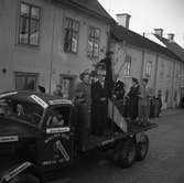 Rollnes Åkeri deltar i Barnens Dagsfirandet. En man och två barn sitter i förarhytten. På lastbilen är det klistrat lappar med texten 