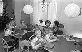 Barnträdgården, Arbetarnas Bildningsförbund, ABF, på Stadsgården. Barnen sitter vid två bord och syr snögubbar av garn på pappskivor. En 