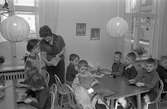 Barnträdgård, Arbetarnas Bildningsförbund, ABF, på Stadsgården. Barnen sitter vid borden och syr snögubbar av garn på pappskivor. 