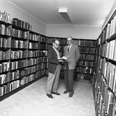 Biblioteket. Mannen till höger är stadsbibliotekarie Östen Bengtsson. Den andre mannen kan heta Ekman.
Stadsbiblioteket ligger i Stadsgården vid Stora torget.
Två män står i ett rum fullt av bokhyllor och böcker.
