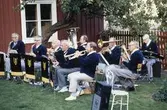 Blåsorkester som uppträder i trädgården till Västerlånggatan 1