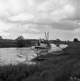 En båt på Arbogaån. Två håvbåtar vilar i vassen.