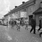 Casinorevyn i parad på Nygatan. Kvinnor bär skyltar om att det spelas fotbollsmatch på Sturevallen och att det blir ett nöje för hela familjen.