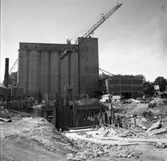 Centralföreningen bygger nytt. Lyftkran och bräder. Silon i bakgrunden.